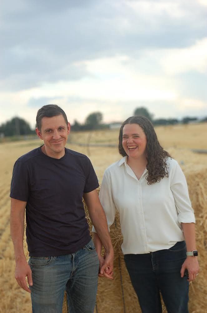 Picture of husband and wife holding hands while walking through a wheat field